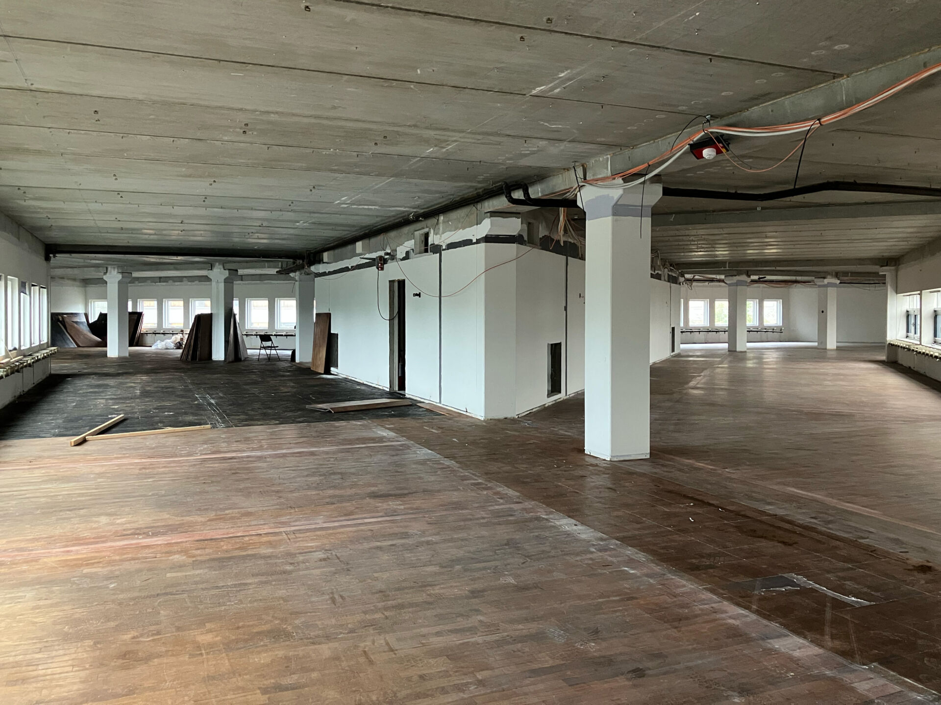 Left: Picture showing one of the floors with the triangular service core in the center. Right: Picture of one of the top floors, with a higher sloped ceiling and skylight. Both pictures are taken of the building in the state of a soft strip of materials and with the glazed facade on the right side. © Line Kjær Frederiksen.